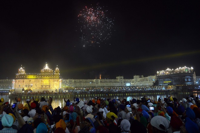 Sikh devotees watch a fireworks display at the Golden Temple in Amritsar on October 17, 2016 during an event to mark the birth anniversary of the fourth Sikh Guru Ramdas.