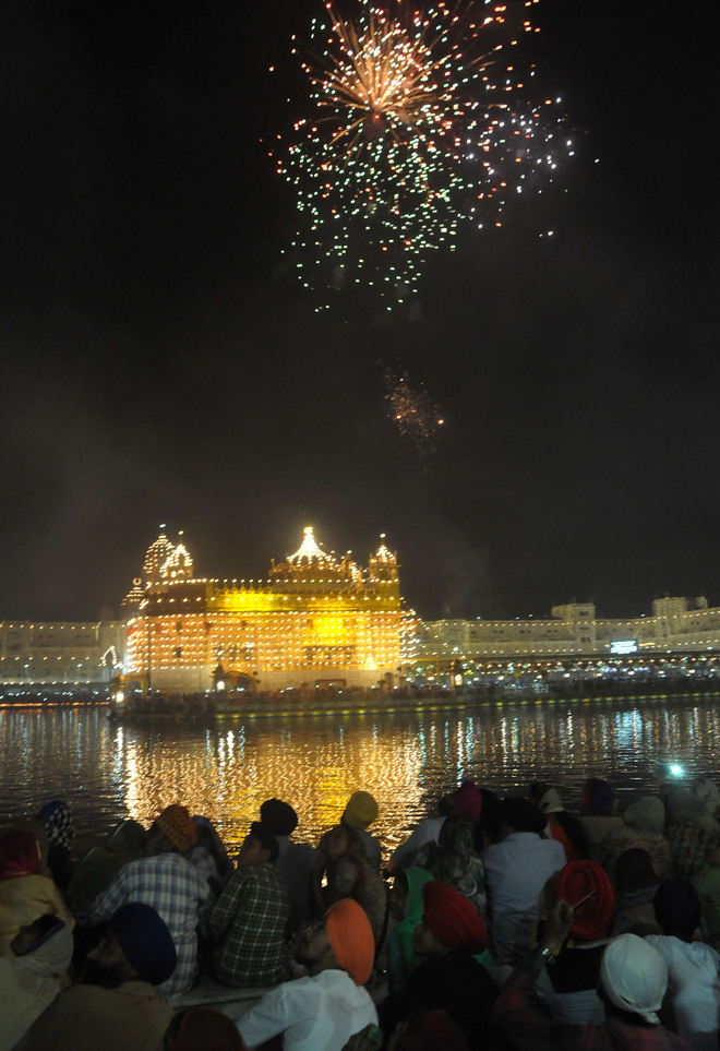 Sikh devotees watch a fireworks display at the Golden Temple in Amritsar on October 17, 2016 during an event to mark the birth anniversary of the fourth Sikh Guru Ramdas.