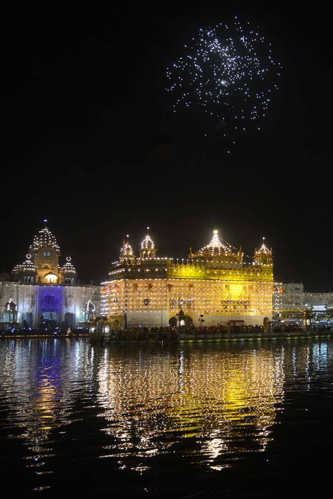 Sikh devotees watch a fireworks display at the Golden Temple in Amritsar on October 17, 2016 during an event to mark the birth anniversary of the fourth Sikh Guru Ramdas.