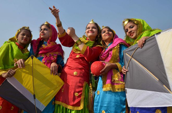 Young girls pose as they fly kites during celebrations on the eve of the Lohri festival in Amritsar