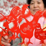 A folk craftswoman Feng Shiping shows a paper cutting of a rooster she made for the upcoming Chinese New Year in Handan, north China's Hebei province