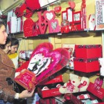 A girl picks up a card on the eve of Valentine's Day at a gift shop ans Shiv Sena activists burn greeting cards during a protest against Valentine's Day