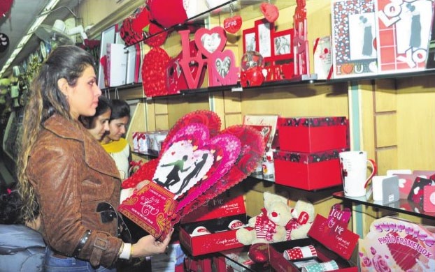 A girl picks up a card on the eve of Valentine's Day at a gift shop ans Shiv Sena activists burn greeting cards during a protest against Valentine's Day