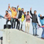 Boys stand on a parapet while flying kites in Bathinda