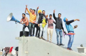 Boys stand on a parapet while flying kites in Bathinda