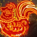 Chinese men walk past neon decorations marking the Year of the Rooster in Beijing