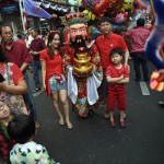 People pose for a picture with a man in festive costume on the occasion of the Lunar New Year in Bangkok's Chinatown on February 8, 2016. The Lunar New Year marks the start of the year of the monkey and is widely celebrated throughout Thailand where 14 percent of the population is ethnic Chinese.
