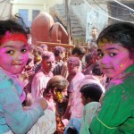 Children look at a religious procession on Holi at the Durgiana Temple