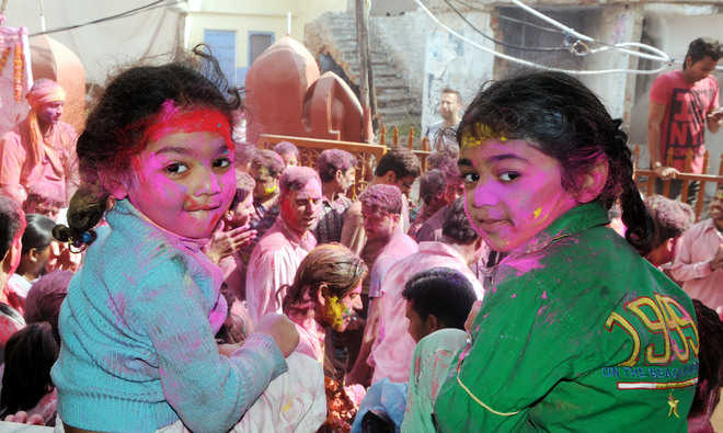 Children look at a religious procession on Holi at the Durgiana Temple