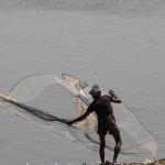 A Pakistani fisherman uses a net to try to catch fish on a riverbank in Lahore