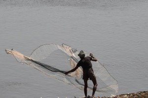 A Pakistani fisherman uses a net to try to catch fish on a riverbank in Lahore