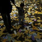 A father holds hands with his son and as they walk over offerings and paper money while thousands of Yeh family members attend an annual worship ceremony to pay respects to their ancestors during the Qingming Festival, or Tomb Sweeping Day, in Taoyuan, Taiwan, on April 4, 2016