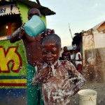 A man gives a bath to his son (6) in the neighborhood of Cite Vincent in the commune of Cite Soleil in the Haitian capital Port-au-Prince