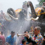 A man plays a trumpet while people are splashed by elephants with water during the celebration of the Songkran water festival in Thailand's Ayutthaya province, north of Bangkok, on April 11, 2016
