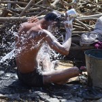 A man takes a bath after collecting water from a road side tap in Allahabad