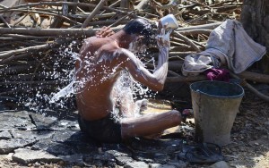 A man takes a bath after collecting water from a road side tap in Allahabad