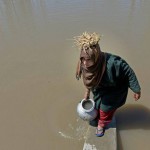 A woman collects water for drinking and cooking from a canal in Srinagar