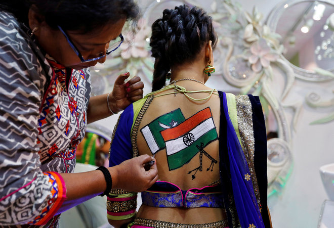 An artist applies final touches to a tattoo sketched on the back of a woman depicting India and Pakistan flags in preparations for the upcoming Navratri, a festival when devotees worship the Hindu goddess Durga and youths dance in traditional costumes in Ahmedabad, India, on September 26, 2016.