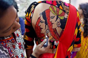An artist applies final touches to a tattoo sketched on the back of a woman in preparations for the upcoming Navratri, a festival when devotees worship the Hindu goddess Durga and youths dance in traditional costumes in Ahmedabad, India, on September 26, 2016.
