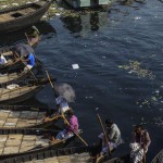 Bangladeshi boatmen wait for commuters next to the polluted water of the Burignaga river in Dhaka