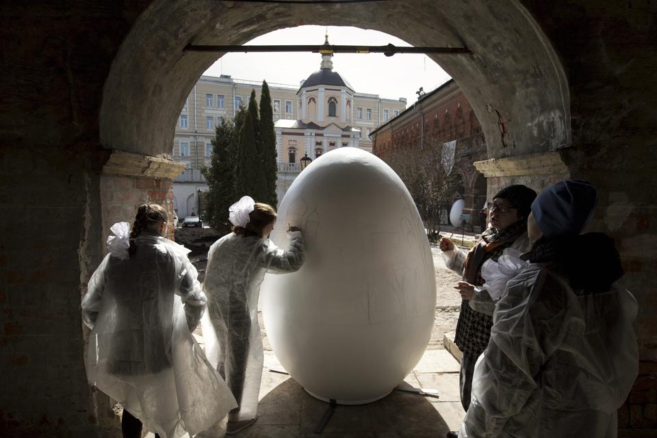 Children paint a huge symbolic egg in preparation for Orthodox Easter, after the Palm Sunday mass at the St. Peter's Cathedral in the High-Petrovsky monastery in Moscow, Russia