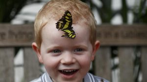 Luca Wainwright, aged 3, smiles as he poses for a photograph with a butterfly during an event to launch the Sensational Butterflies exhibition