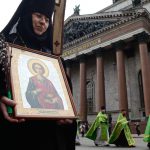 Russian Orthodox nun carries an icon during the Palm Sunday procession outside the Saint Isaac's Cathedral in Saint Petersburg, on April 9, 2017