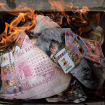 So called 'spirit money' burns next to a grave as an offering during the annual Qingming festival, or Tomb Sweeping Day, at a public cemetery in Shanghai on April 4, 2016