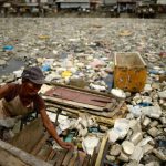 Teresita Gapayao, 51, a scavenger for 12 years, wades through garbage using a makeshift raft made from styrofoam on the Estero de Vitas tiver in Tondo, Manila ahead of World Earth Day on April 21, 2016