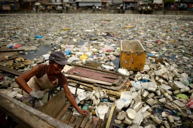 Teresita Gapayao, 51, a scavenger for 12 years, wades through garbage using a makeshift raft made from styrofoam on the Estero de Vitas tiver in Tondo, Manila ahead of World Earth Day on April 21, 2016