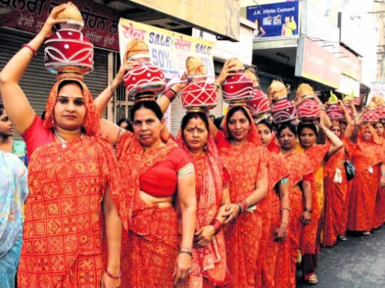 Women hold ceremonial pots over their heads