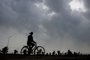 A cyclist rides past as pre-monsoon clouds loom over Karnal’s sky