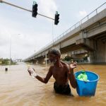 A man carries water and food in a bucket as they walk through a flooded road in Kaduwela, Sri Lanka on May 20.