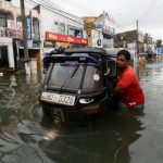 A man pushes his trishaw through a flooded road in Wellampitiya, Sri Lanka May 21