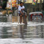 A man sits on a chair as he uses a piece of styrofoam to move through a flooded road in Wellampitiya, Sri Lanka May 21.
