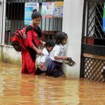 A woman and her children wade through floodwater heavy rain in Guwahati on June 16, 2016.