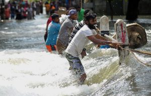 Flood-affected Sri Lankans struggle to cross a torrent of floodwaters in Kelaniya, on the outskirts of Colombo on May 21.