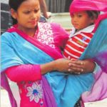 On the eve of Mother's Day a woman wraps her child with a chunni to protect him from the scorching heat in Amritsar
