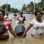 Sri Lankan flood victims carry food parcels and drinking water through floodwaters in the suburb of Kaduwela in Colombo