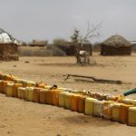 A man fills a long line of plastic water containers from a tanker, in the drought-affected village of Bandarero