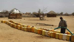 A man fills a long line of plastic water containers from a tanker, in the drought-affected village of Bandarero