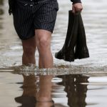 A man holds boots as he walks in a flooded street in Montargis in the Loiret, following heavy rain in France June 1.