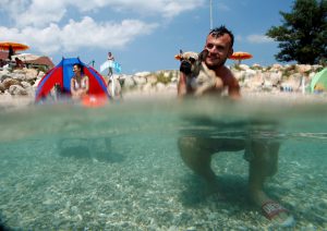 A man is pictured with his dog at the dog beach and bar in Crikvenica, Croatia, July 12, 2016. The first Croatian beach bar specifically designed for dogs opens in the northern Adriatic town of Crikvenica, enabling canines and their owners to experience the joys of summertime together. Located at one of the few dog friendly beaches in the country, the bar's offer includes specially prepared ice cream, dog beer and snacks.