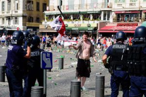 A police officer throws a George Flag back to an England fan during fights between English, Russian and French groups in Marseille, on June 11, 2016, on the sideline of the Euro 2016 European football championships.