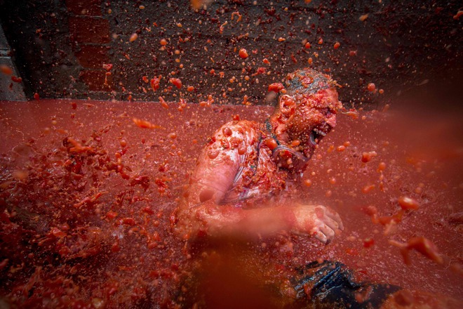 A reveller is pelted with tomato pulp during the annual