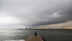 A woman stands on a seaside promenade against the background of pre-monsoon clouds gathered over the Arabian Sea in Kochi