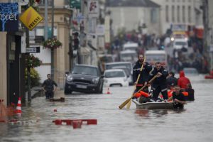 French firefighters use a small boat to evacuate residents from a flooded area after heavy rainfall in Nemours, June 1.