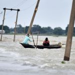 Indian villagers paddle a boat along a submerged road in the flood-affected Ashighar village in the northeastern state of Assam on July 5, 2016
