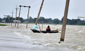 Indian villagers paddle a boat along a submerged road in the flood-affected Ashighar village in the northeastern state of Assam on July 5, 2016