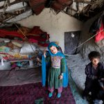 Internally-displaced Afghan children stand inside their shelter at a refugee camp in Kabul, Afghanistan, on May 31, 2016.